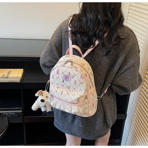 Détail du sac à dos avec motifs lapins, dentelle et breloque en peluche de chiot blanc