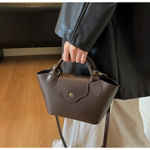 Macro shot of dark brown lychee texture leather handbag with gold metal clasp