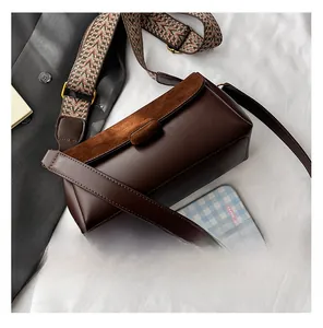 Detail showing the brown crossbody bag with suede texture and woven wide shoulder strap