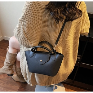 Chic black litchi pattern dumpling bag worn with casual knitwear in a cozy setting