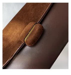 Macro shot of dark brown matte suede and smooth leather texture with oval buckle detail