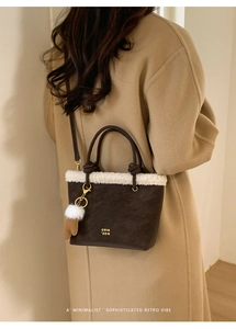 Close-up of deep brown tote bag with white shearling trim and cute plush pendant