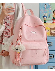Detailed view of pink polka dot backpack with plush dog charm and brand label
