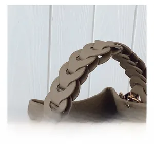 Détail du sac seau en cuir kaki avec poignée tressée et finitions métalliques dorées