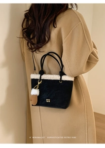 Detail of suede bucket bag with shearling trim and plush glove charm on wool coat