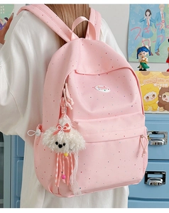 Close-up of pink polka dot backpack with a cute white puppy plush charm for school