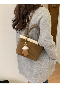 Detail view of brown suede bucket bag with white faux shearling trim and heart charm