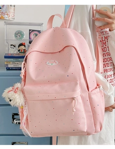 Detailed view of pink polka dot backpack featuring a cute plush dog pendant charm