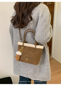 Detail of suede bucket bag with faux shearling trim and cute glove pendant accessory