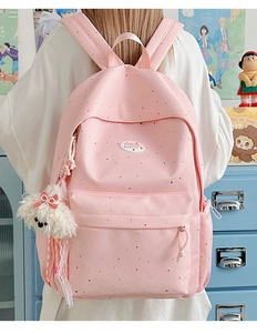 Detailed shot of a light pink polka dot backpack with a cute plush dog pendant charm