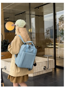 Light blue faux leather backpack with cross-hatch texture on modern urban street background