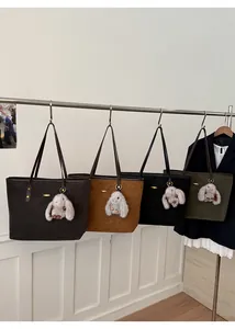 Détail de sacs fourre-tout en daim en quatre couleurs avec breloques lapin en peluche