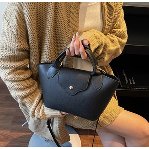 Close-up of black lychee leather crossbody bag with metal magnetic buckle and handle
