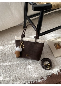 Detail of winter shoulder bag with brown leather, creamy faux fur trim and knot handle