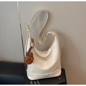 Detail of cream PU leather hobo bag with gold buckle and brown teddy bear charm accessory