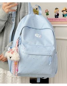 Detail of light blue polka dot backpack with a cute plush dog pendant and brand logo