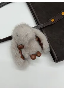 Détail d'un porte-clé lapin en fausse fourrure grise sur un sac cabas en daim marron