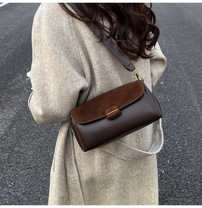 Detail of dark brown shoulder bag with suede flap and smooth leather texture finish