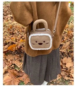 Close-up of brown plush crossbody bag with cartoon embroidery and fuzzy trim