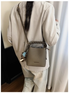 Detail of light brown bucket bag with lychee texture and cute plush bear charm decoration