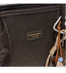 Détail d'un cabas en cuir marron foncé avec surpiq coutures blanches et breloques de sac stylées