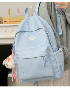 Detail of light blue polka dot backpack with a cute white plush bear keychain accessory