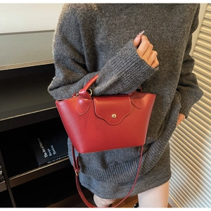 Detail of red lychee pattern leather handbag with gold metal snap and round handle
