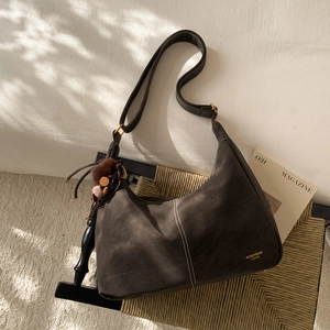 Macro detail of dark brown matte Hobo bag with tassel charm and brand logo