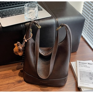 Detailed texture of dark brown pebbled leather tote bag with a cute bear charm