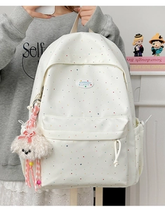 Detailed close-up of polka dot backpack with plush puppy charm and rainbow moon pattern