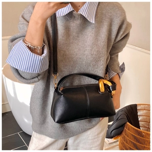 Détail du sac en cuir noir avec une boucle décorative en chaîne dorée sur la poignée