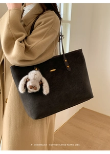 Détail du grand sac cabas noir en daim avec boucles dorées et breloque lapin en peluche