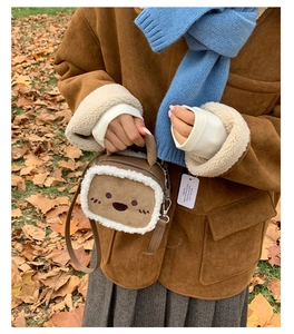 Close-up of brown plush crossbody bag featuring cute cartoon embroidery and lamb wool trim
