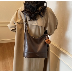 Detail of a brown hobo shoulder bag with retro texture and a cute plush bear charm