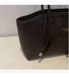 Détail du cabas en daim marron foncé avec surpiqûres contrastées et garniture en métal