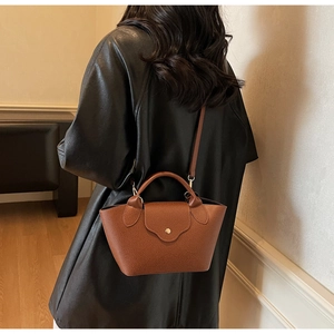 Close-up of brown litchi pattern leather bag showing texture and golden snap button detail