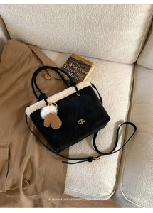 Detail of suede bucket bag with faux fur trim, gold logo and decorative heart charm
