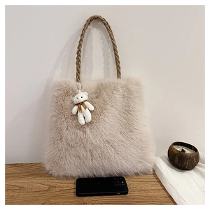 Detail of fuzzy beige tote bag with braided brown handle and cute bear charm accent