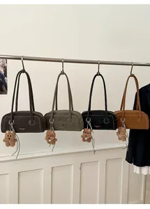 Row of minimalist suede crossbody bags in dark coffee, green, black and tan with bear charm