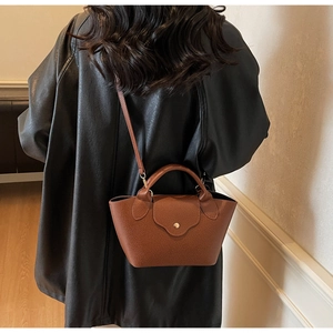Detail of caramel lychee grain leather handbag with top handle and fine shoulder strap