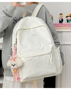 Detail of white star pattern backpack with plush dog charm and braided cord accents
