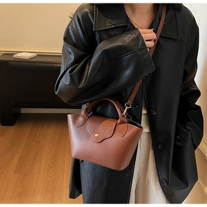 Detail of vintage brown leather handbag with pebble texture and gold metal buckle closure