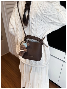 Detail of coffee brown bucket bag with lychee grain leather and woven chain handle