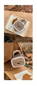 Brown suede cartoon embroidered plush handbag with fuzzy trim shown in autumn setting