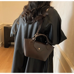 Detail of a dark brown lychee leather tote bag with gold metal buckle and shoulder strap
