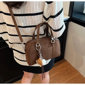 Brown Boston bag with matte texture and baseball charm shown in a lifestyle pose