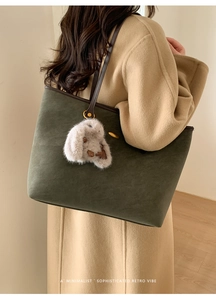 Détail du sac cabas en daim vert foncé avec anses en cuir marron et breloque lapin