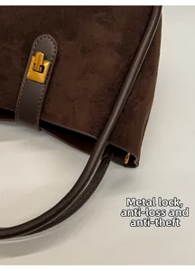 Gros plan d'un sac à main en daim marron foncé avec un fermoir doré sécurisé