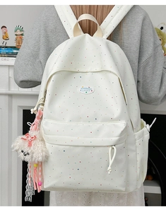Close-up of white polka dot backpack with a cute white dog plush pendant on side