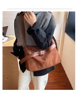 Détail de la texture suédée mate marron et de la boucle en métal argenté du sac cabas